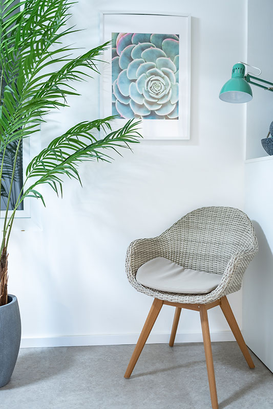 Wartebereich, heller moderner Stuhl, Bild an der Wand, Pflanze links angeschnitten